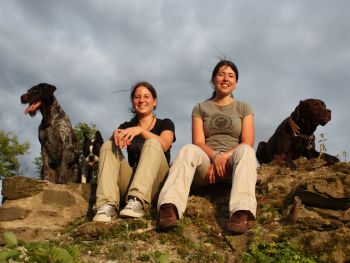 Die Trainer Ramona und Melanie sitzen mit ihren Hunden auf den Mauerresten der Ruine Waldenburg